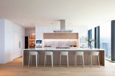 Example of a large minimalist l-shaped medium tone wood floor eat-in kitchen design in Hawaii with an undermount sink, flat-panel cabinets, marble countertops, white appliances, an island and white countertops