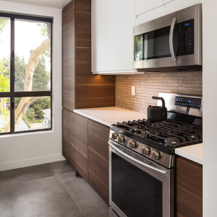 Diseño de cocina de galera, actual, pequeña, cerrada, sin isla, con fregadero bajoencimera, armarios con paneles lisos, puertas de armario de madera en tonos medios, encimera de cuarzo compacto, salpicadero verde, salpicadero de piedra caliza, electrodomésticos de acero inoxidable, suelo de cemento, suelo gris y encimeras blancas