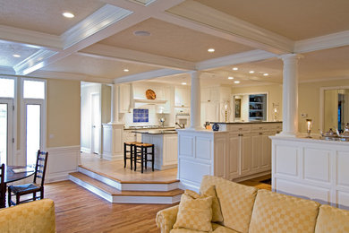 Eat-in kitchen - mid-sized traditional galley medium tone wood floor eat-in kitchen idea in Cleveland with raised-panel cabinets, white cabinets, white backsplash, an island, granite countertops, glass tile backsplash, stainless steel appliances and a double-bowl sink