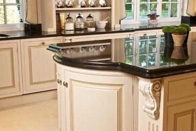 ハンプシャーにあるトラディショナルスタイルのおしゃれなアイランドキッチン (レイズドパネル扉のキャビネット、黒いキャビネット、パネルと同色の調理設備、ベージュの床) の写真