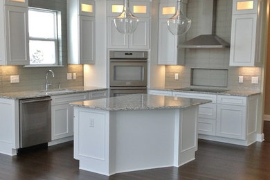 Mid-sized trendy l-shaped medium tone wood floor eat-in kitchen photo in Cleveland with an undermount sink, recessed-panel cabinets, white cabinets, granite countertops, gray backsplash, cement tile backsplash, stainless steel appliances and an island