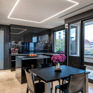 This is an example of a contemporary l-shaped eat-in kitchen in Perth with flat-panel cabinets, black cabinets, black splashback, black appliances, with island, beige floor and black benchtop.