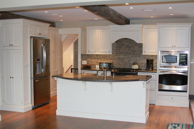 Inspiration for a large timeless l-shaped open concept kitchen remodel in Boston with a farmhouse sink, beaded inset cabinets, white cabinets, solid surface countertops, stainless steel appliances, an island and gray backsplash