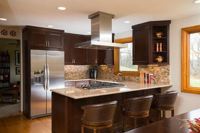 Inredning av ett amerikanskt mellanstort linjärt kök och matrum, med en undermonterad diskho, luckor med infälld panel, skåp i mörkt trä, beige stänkskydd, rostfria vitvaror, mellanmörkt trägolv och en halv köksö