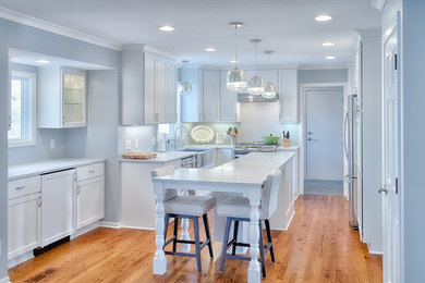 Eat-in kitchen - small traditional galley light wood floor eat-in kitchen idea in Minneapolis with a farmhouse sink, recessed-panel cabinets, white cabinets, quartz countertops, gray backsplash, stainless steel appliances and an island