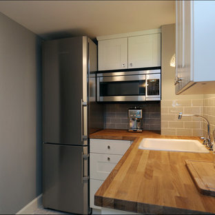 This is an example of a small transitional l-shaped separate kitchen in Portland with a single-bowl sink, recessed-panel cabinets, white cabinets, wood benchtops, grey splashback, subway tile splashback, stainless steel appliances, marble floors and no island.