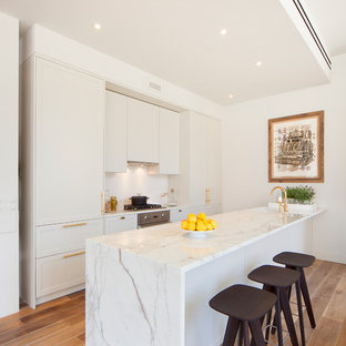 Mid-sized modern open concept kitchen photos - Open concept kitchen - mid-sized modern galley medium tone wood floor open concept kitchen idea in New York with a single-bowl sink, shaker cabinets, white cabinets, marble countertops, white backsplash, stainless steel appliances and a peninsula