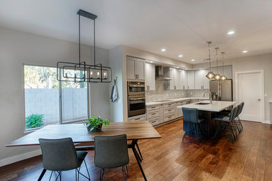 Eat-in kitchen - mid-sized modern l-shaped eat-in kitchen idea with an undermount sink, shaker cabinets, white cabinets, quartz countertops, multicolored backsplash, stainless steel appliances and an island