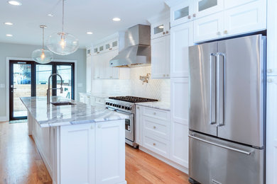 Example of a mid-sized transitional galley brown floor and medium tone wood floor open concept kitchen design in Philadelphia with an undermount sink, recessed-panel cabinets, white cabinets, marble countertops, white backsplash, marble backsplash, stainless steel appliances, an island and white countertops