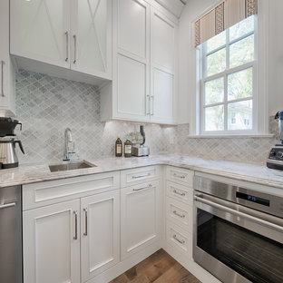 Photo of a large transitional u-shaped kitchen pantry in Philadelphia with multiple islands, recessed-panel cabinets, white cabinets, marble benchtops, grey splashback, mosaic tile splashback, stainless steel appliances, an integrated sink and medium hardwood floors.