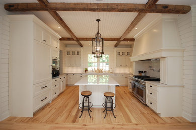 Inspiration for a large timeless u-shaped light wood floor eat-in kitchen remodel in Ottawa with a farmhouse sink, recessed-panel cabinets, white cabinets, quartz countertops, white backsplash, stone tile backsplash, paneled appliances and an island