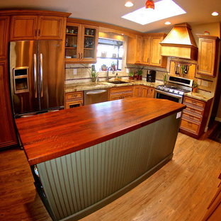 Design ideas for a mid-sized country l-shaped open plan kitchen in San Diego with an integrated sink, flat-panel cabinets, medium wood cabinets, granite benchtops, beige splashback, ceramic splashback, stainless steel appliances, light hardwood floors and with island.
