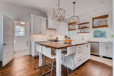 Mid-sized country u-shaped dark wood floor and brown floor enclosed kitchen photo in Baltimore with a farmhouse sink, recessed-panel cabinets, white cabinets, white backsplash, subway tile backsplash, stainless steel appliances and an island