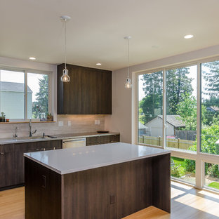 Mid-sized modern l-shaped open plan kitchen in Seattle with an integrated sink, flat-panel cabinets, dark wood cabinets, quartz benchtops, beige splashback, porcelain splashback, stainless steel appliances, bamboo floors and with island.