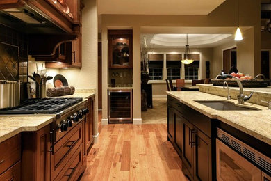 Enclosed kitchen - large transitional l-shaped light wood floor and brown floor enclosed kitchen idea in Boston with an undermount sink, recessed-panel cabinets, dark wood cabinets, granite countertops, black backsplash, ceramic backsplash, stainless steel appliances, an island and beige countertops