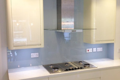 Diseño de cocina actual con salpicadero azul y salpicadero de vidrio templado