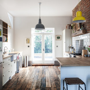Immagine di una piccola cucina parallela country con lavello stile country, ante bianche, top in legno, paraspruzzi bianco, paraspruzzi con piastrelle diamantate, elettrodomestici in acciaio inossidabile, parquet scuro e penisola