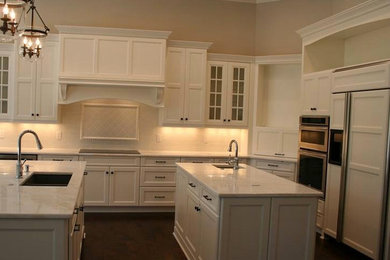 アトランタにあるトラディショナルスタイルのおしゃれなマルチアイランドキッチン (白いキャビネット、大理石カウンター、白いキッチンパネル) の写真