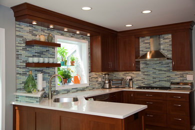 Photo of a medium sized modern u-shaped open plan kitchen in Chicago with a submerged sink, shaker cabinets, medium wood cabinets, engineered stone countertops, multi-coloured splashback, glass tiled splashback, stainless steel appliances, light hardwood flooring and a breakfast bar.