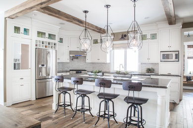 Farmhouse l-shaped light wood floor and brown floor kitchen photo in Cleveland with recessed-panel cabinets, white cabinets, gray backsplash, brick backsplash, stainless steel appliances and an island