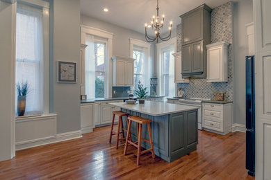 Mid-sized transitional u-shaped medium tone wood floor eat-in kitchen photo in St Louis with an undermount sink, raised-panel cabinets, quartz countertops, multicolored backsplash, paneled appliances, an island and multicolored countertops