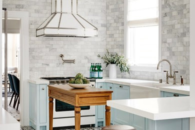 Example of a transitional u-shaped multicolored floor kitchen design in San Francisco with a farmhouse sink, shaker cabinets, blue cabinets, gray backsplash, marble backsplash, white appliances, an island and white countertops