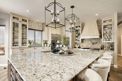 Large transitional l-shaped porcelain tile and brown floor open concept kitchen photo in Denver with an undermount sink, raised-panel cabinets, white cabinets, quartz countertops, multicolored backsplash, stone tile backsplash, stainless steel appliances, an island and multicolored countertops