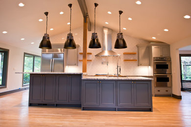 Large urban light wood floor open concept kitchen photo in Seattle with a farmhouse sink, beaded inset cabinets, gray cabinets, granite countertops, white backsplash, porcelain backsplash, stainless steel appliances and two islands