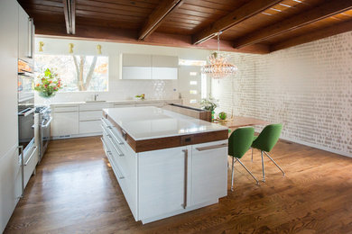 Inspiration for a mid-sized mid-century modern l-shaped medium tone wood floor, brown floor and wood ceiling eat-in kitchen remodel in DC Metro with an undermount sink, flat-panel cabinets, white cabinets, white backsplash, paneled appliances, an island, white countertops, quartz countertops and ceramic backsplash