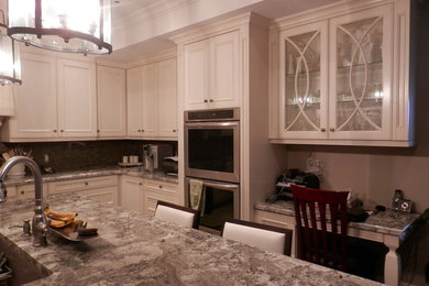Ejemplo de cocina clásica grande con armarios con rebordes decorativos, puertas de armario blancas, encimera de granito, salpicadero marrón y electrodomésticos de acero inoxidable