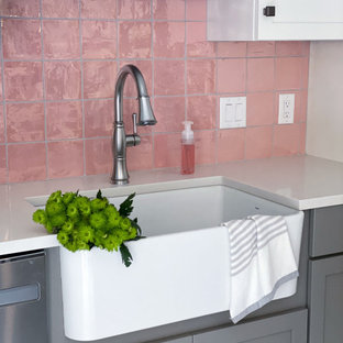 This is an example of a transitional eat-in kitchen in Boston with a farmhouse sink, shaker cabinets, white cabinets, quartz benchtops, pink splashback, ceramic splashback, stainless steel appliances, porcelain floors, with island, white floor and white benchtop.