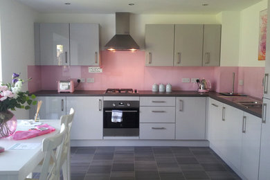 他の地域にあるコンテンポラリースタイルのおしゃれなキッチン (ピンクのキッチンパネル、ガラス板のキッチンパネル) の写真