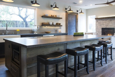 Inspiration for a mid-sized farmhouse l-shaped dark wood floor and brown floor eat-in kitchen remodel in Sacramento with a farmhouse sink, shaker cabinets, black cabinets, quartz countertops, beige backsplash, ceramic backsplash, stainless steel appliances and an island