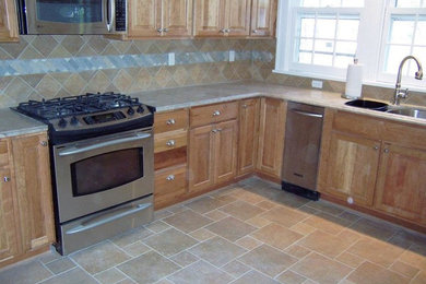 Inspiration for a transitional u-shaped ceramic tile kitchen remodel in New York with a double-bowl sink, medium tone wood cabinets, multicolored backsplash, ceramic backsplash, stainless steel appliances, raised-panel cabinets and marble countertops