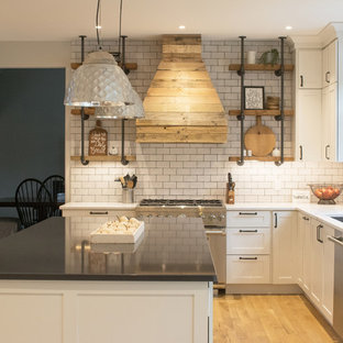 Large farmhouse eat-in kitchen appliance - Large country u-shaped light wood floor and brown floor eat-in kitchen photo in Grand Rapids with an undermount sink, shaker cabinets, white cabinets, quartz countertops, white backsplash, subway tile backsplash, stainless steel appliances and an island