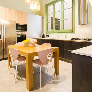 Modelo de cocina comedor ecléctica con armarios con paneles lisos, puertas de armario negras, salpicadero blanco, salpicadero de losas de piedra, electrodomésticos de acero inoxidable y encimeras blancas