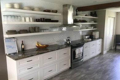 Example of a mid-sized trendy galley porcelain tile and gray floor eat-in kitchen design in Toronto with a double-bowl sink, shaker cabinets, white cabinets, quartz countertops, white backsplash, porcelain backsplash, stainless steel appliances and no island