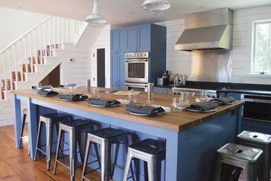 Exempel på ett lantligt kök, med skåp i shakerstil, blå skåp, träbänkskiva, stänkskydd i trä och rostfria vitvaror