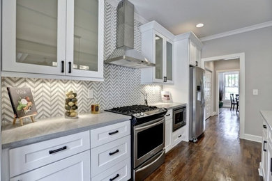 Example of a classic medium tone wood floor kitchen design in Atlanta with white cabinets, gray backsplash and stainless steel appliances