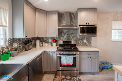 Large trendy u-shaped laminate floor and white floor eat-in kitchen photo in Los Angeles with a double-bowl sink, shaker cabinets, gray cabinets, quartz countertops, multicolored backsplash, mosaic tile backsplash, stainless steel appliances, an island and beige countertops