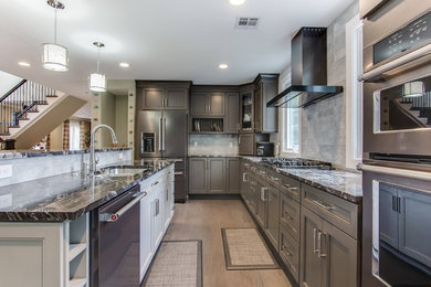 Large transitional u-shaped medium tone wood floor and brown floor open concept kitchen photo in New York with an undermount sink, recessed-panel cabinets, green cabinets, granite countertops, gray backsplash, stone tile backsplash, stainless steel appliances and an island