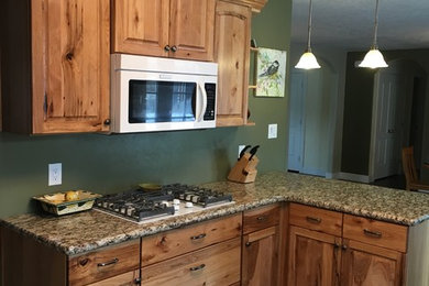 Eat-in kitchen - mid-sized southwestern dark wood floor eat-in kitchen idea in Albuquerque with raised-panel cabinets, light wood cabinets, granite countertops, green backsplash, white appliances and a peninsula