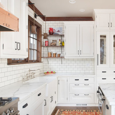 Large transitional l-shaped dark wood floor enclosed kitchen photo in Kansas City with a farmhouse sink, recessed-panel cabinets, white cabinets, marble countertops, white backsplash, subway tile backsplash, stainless steel appliances and an island