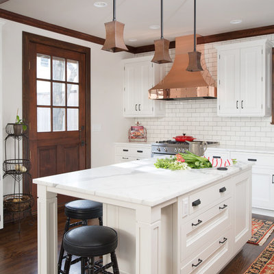 Inspiration for a large transitional l-shaped dark wood floor enclosed kitchen remodel in Kansas City with a farmhouse sink, recessed-panel cabinets, white cabinets, marble countertops, white backsplash, subway tile backsplash, stainless steel appliances and an island