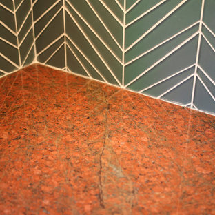 Foto de cocina de galera, actual, pequeña, con despensa, fregadero bajoencimera, armarios con paneles lisos, puertas de armario de madera oscura, encimera de granito, salpicadero azul, salpicadero de azulejos de vidrio, electrodomésticos de acero inoxidable, suelo de madera en tonos medios, una isla, suelo marrón y encimeras naranjas