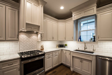Mid-sized elegant u-shaped medium tone wood floor and brown floor enclosed kitchen photo in Other with a single-bowl sink, raised-panel cabinets, gray cabinets, granite countertops, white backsplash, subway tile backsplash, stainless steel appliances and no island