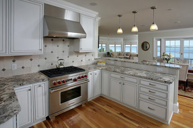 Open concept kitchen - mid-sized traditional u-shaped medium tone wood floor and brown floor open concept kitchen idea in Boston with an undermount sink, beaded inset cabinets, white cabinets, granite countertops, white backsplash, mosaic tile backsplash, stainless steel appliances and a peninsula