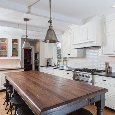 Inspiration for a large transitional l-shaped light wood floor and brown floor eat-in kitchen remodel in Philadelphia with a single-bowl sink, white backsplash, subway tile backsplash, stainless steel appliances, recessed-panel cabinets, white cabinets, an island, soapstone countertops and black countertops