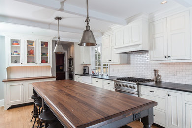 Inspiration for a large transitional l-shaped light wood floor and brown floor eat-in kitchen remodel in Philadelphia with a single-bowl sink, white backsplash, subway tile backsplash, stainless steel appliances, recessed-panel cabinets, white cabinets, an island, soapstone countertops and black countertops