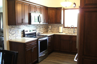 Kitchen - mid-sized traditional u-shaped vinyl floor and gray floor kitchen idea in Milwaukee with an undermount sink, flat-panel cabinets, dark wood cabinets, quartz countertops, white backsplash, mosaic tile backsplash, stainless steel appliances and white countertops